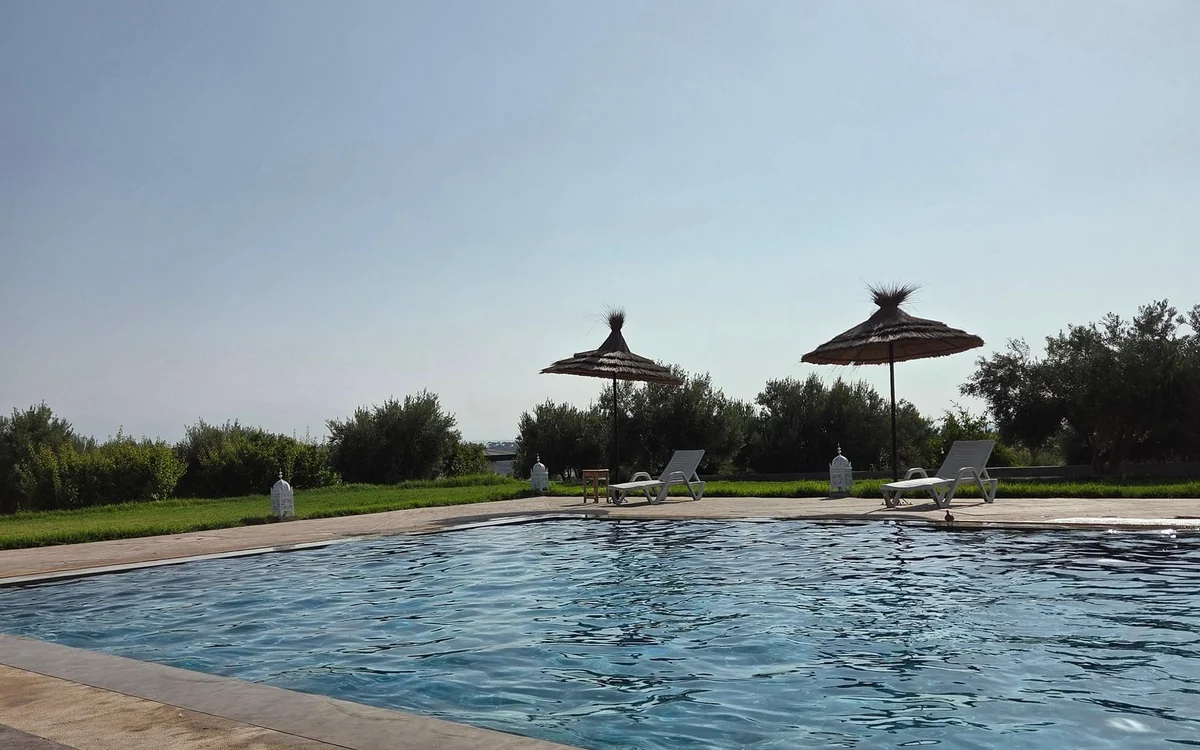 A pool with straw parasols at a camp