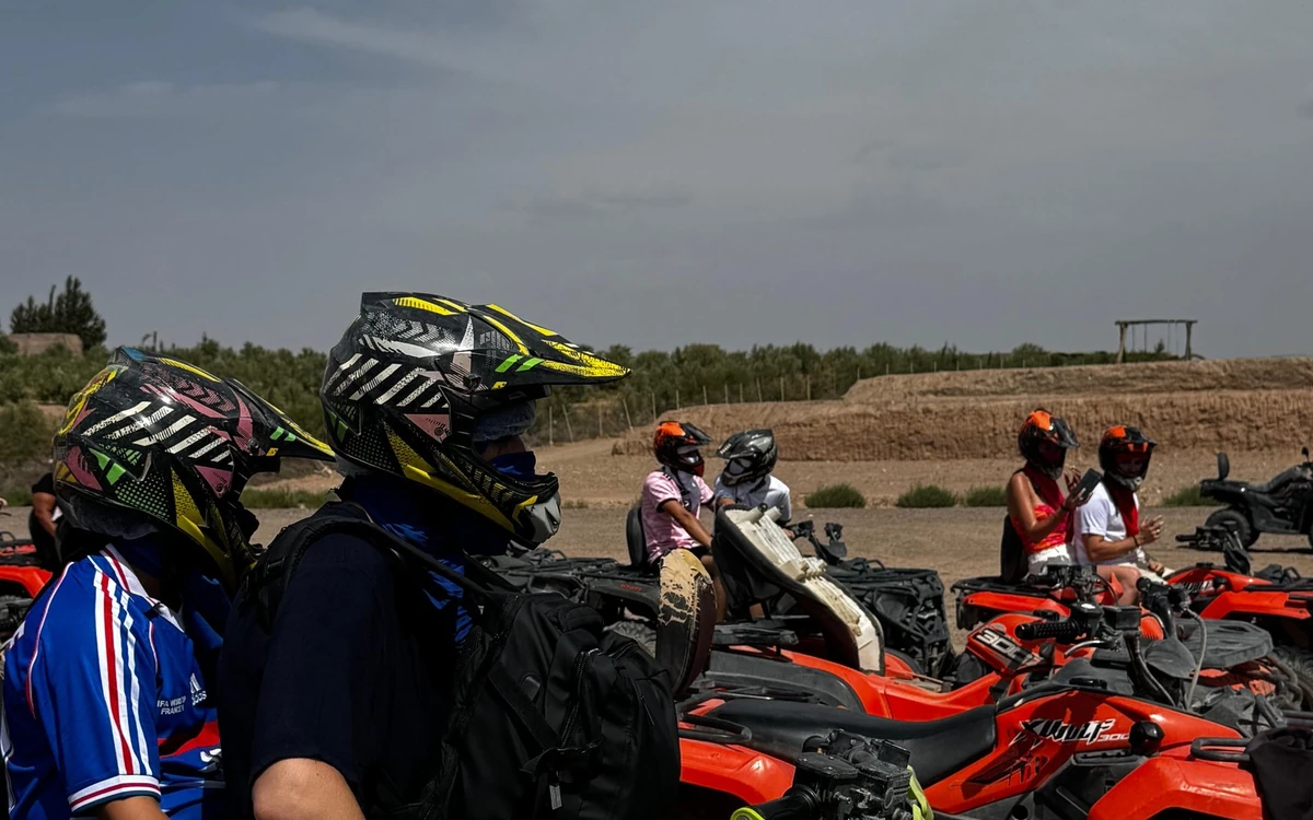 Riders in helmets and goggles standing beside a row of red quad bikes