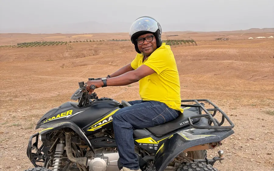 A rider in a helmet on a quad bike in stony desert