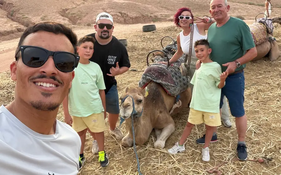 A family posing with their guide and resting camels on the desert ground
